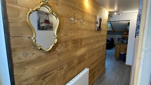 A hallway with wooden paneling, a radiator, and a mirror with an ornate frame.