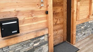 A wooden exterior with a mailbox, a door, and a stone wall.
