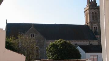 A church with a bell tower and a large tree in front.
