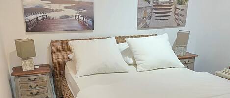 Ein Schlafzimmer mit einem großen Bett, Holzboden und zwei Wandbildern.