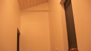 Un couloir étroit avec une porte en bois et une petite fenêtre.