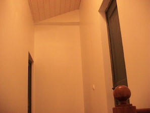 En smal hall med en trädörr och ett litet fönster.