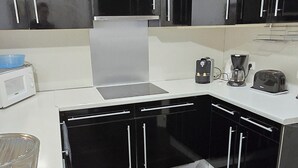 Une cuisine moderne avec des meubles noirs, un plan de travail blanc et un plafond en bois.