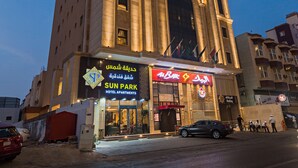 Un hotel con una entrada abovedada destacada y señalización que indica que ofrece habitaciones y apartamentos.
