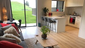 Een moderne woonkamer met een bank, een salontafel en uitzicht op een keuken en een buitenruimte.