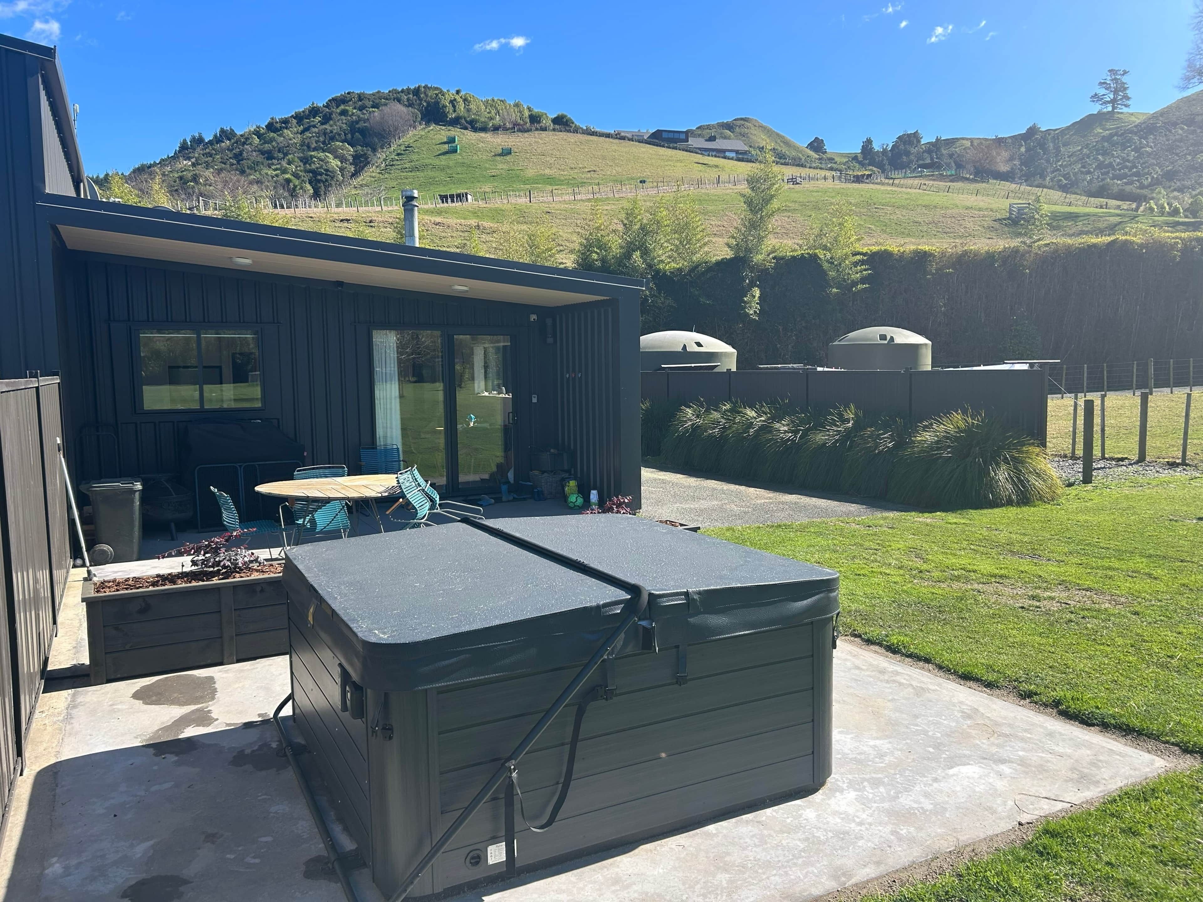 A modern house with a patio, a large outdoor heater, and a view of rolling hills.
