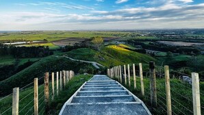 Een trap die een heuvel op leidt, met uitzicht over een landelijk landschap.