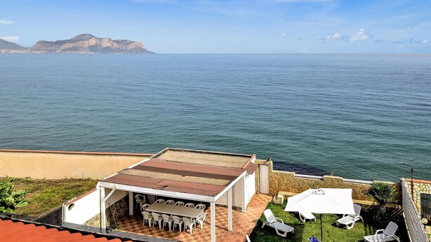 A terrace with a view of the sea and a mountain in the background.