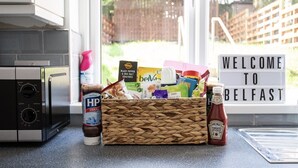 Eine Küchenarbeitsplatte mit einer Korb voller Snacks, Gewürzen und einem Schild mit der Aufschrift 'Welcome to Belfast'.