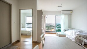 A bedroom with a balcony, a bed, a desk, and a chair.