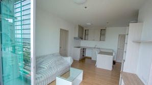 A modern apartment with a living area, kitchenette, and a glass dining table.