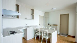 A modern kitchen with white cabinetry, a built-in stove, and a dining area with a white table and chairs.