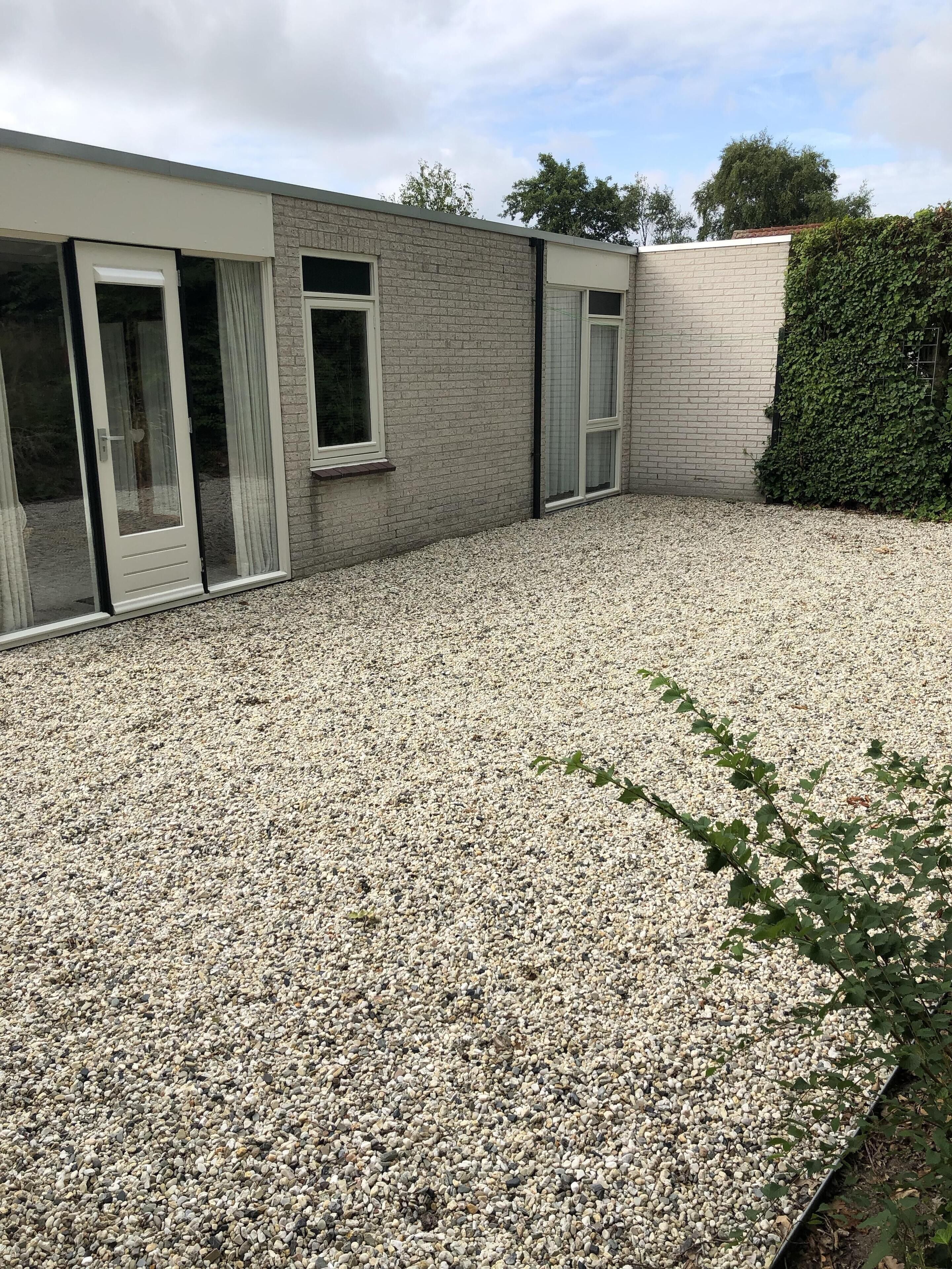 A building with a gravel driveway and a hedge.