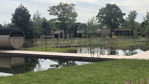 A park with a wooden deck, a pond, and a wooden fence. - Cottage coast in South Holland behind the dunes by the sea (Ouddorp)
