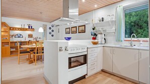 A modern kitchen with white cabinetry, a built-in oven, and a large window offering a view of greenery.