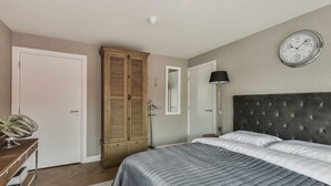Quarto com cama, guarda-roupa, espelho e relógio na parede.