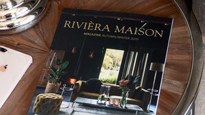 Uma revista com o título "RIVIERA MAISON" sobre uma mesa redonda.