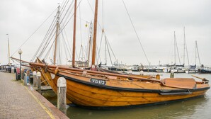 Een houten boot afgemeerd in een jachthaven, met een heldere lucht op de achtergrond.