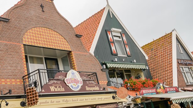 Een traditioneel Nederlands gebouw met een bord voor een bakkerij, een bord voor een restaurant en een bord voor een café.