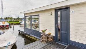 A waterfront property with a dock, a house with a dark blue door, and a sign reading "127 WS7". - Bright and Comfortable Houseboat (Aalsmeer)