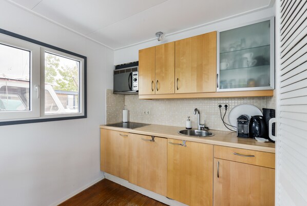 A kitchen with wooden cabinets, a microwave, a sink, and a window.