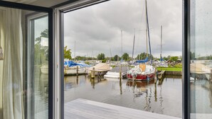 A view of a marina with several boats docked, a wooden deck, and a cloudy sky. - Bright and Comfortable Houseboat (Aalsmeer)
