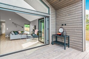 A modern living room with a grey sofa, a coffee table, and a sliding glass door leading to an outdoor area.