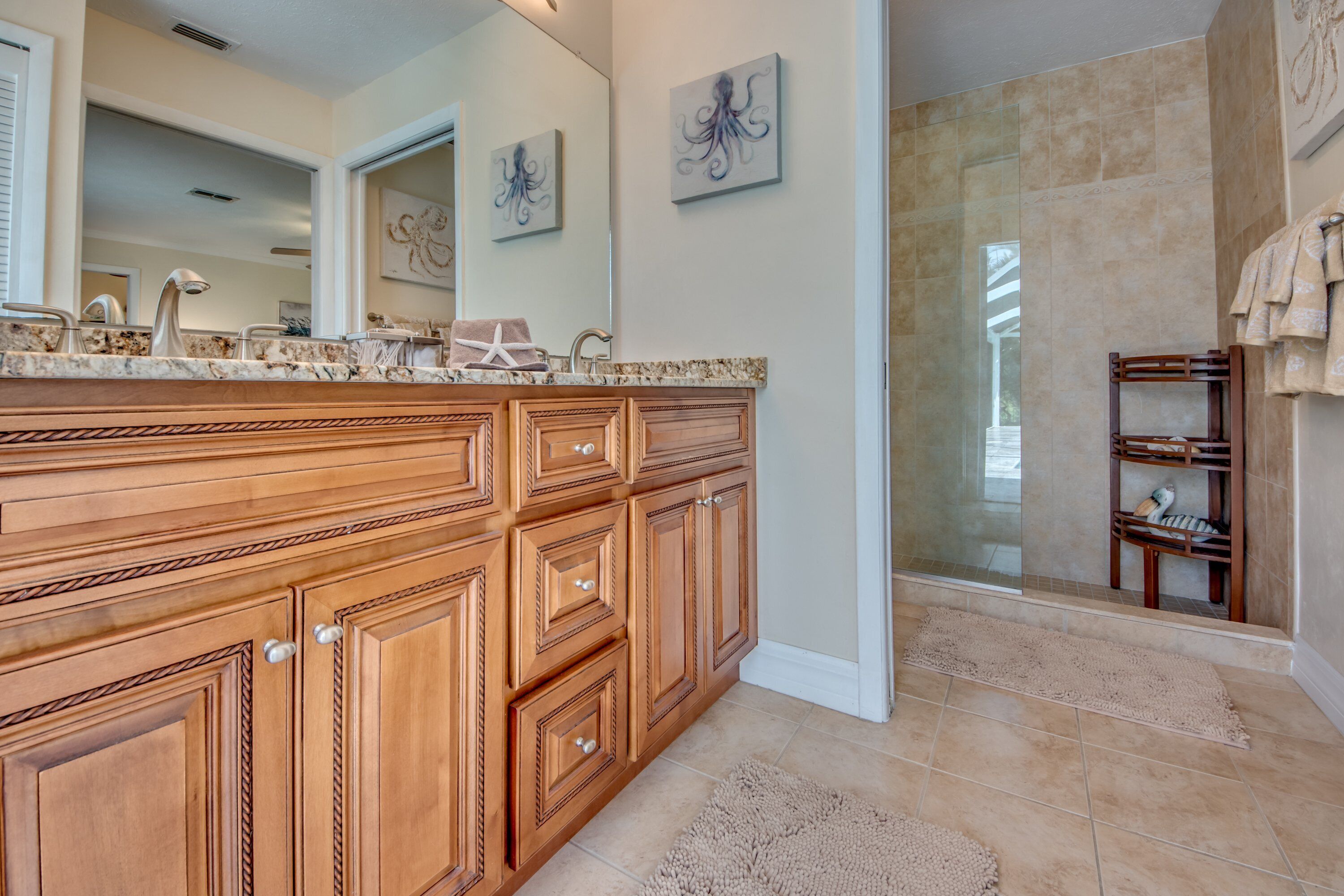 A spacious bathroom with a large wooden vanity, a glass shower enclosure, and a walk-in shower.