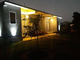 En boligbygning med veranda, et lille træ og en godt oplyst indgang.