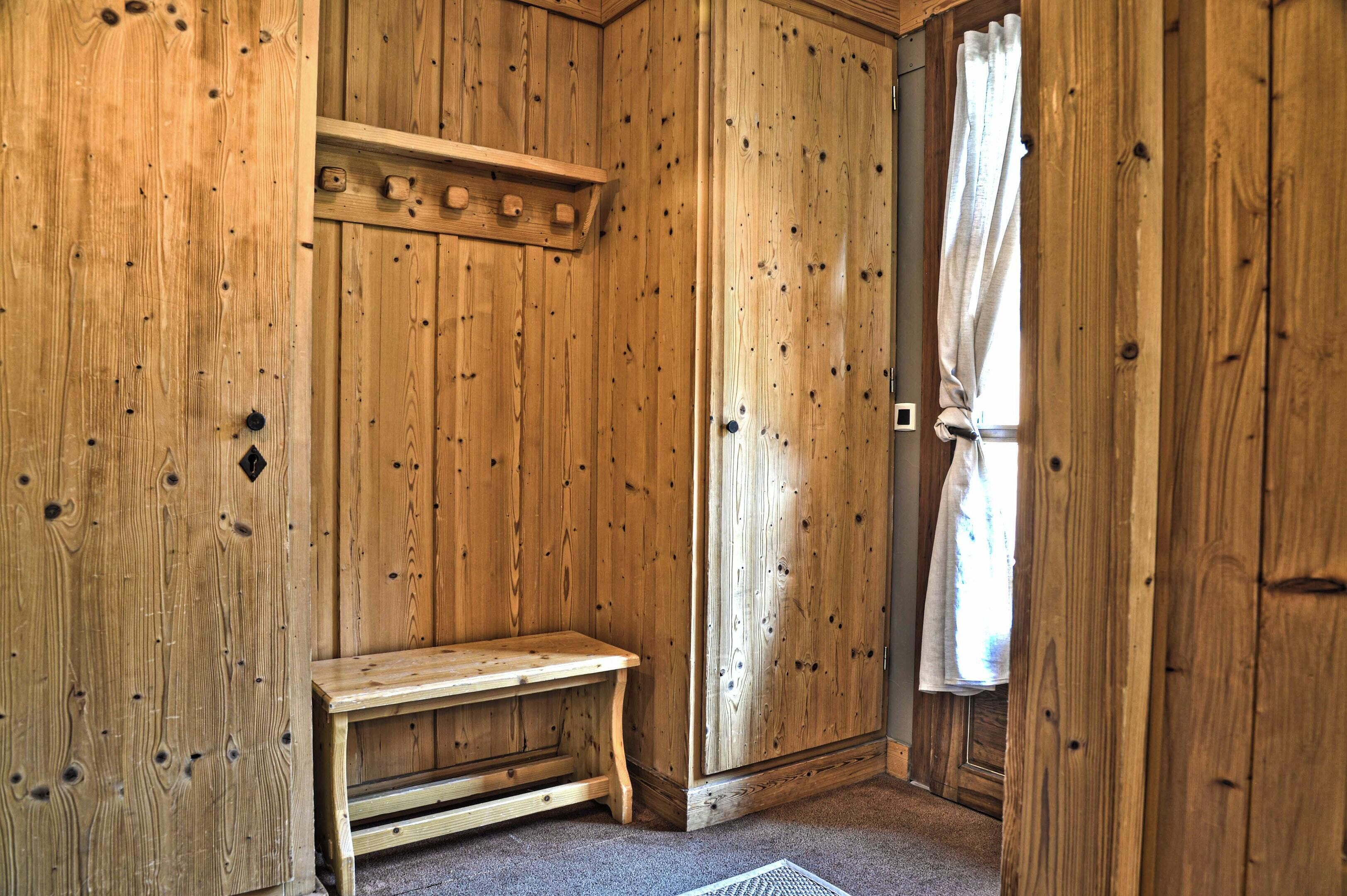 A wooden room with a bench, a shelf, and a door with a curtain.