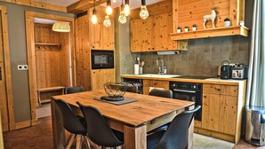 A wooden kitchen with a dining table and chairs, a microwave, stove, sink, and various appliances. - Homerez - Apt. Mountain View - Les Deux Alpes (Les Deux Alpes)