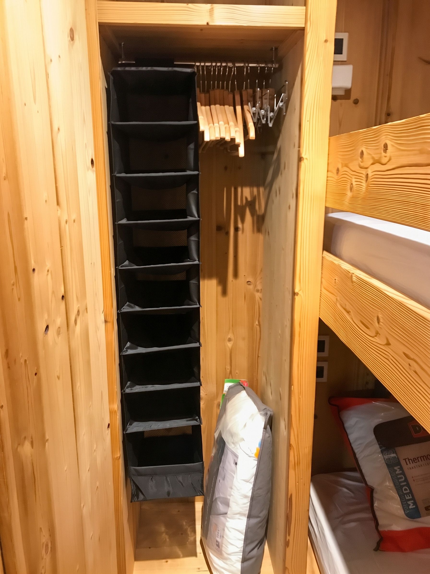 A wooden closet with multiple shelves and hanging space.
