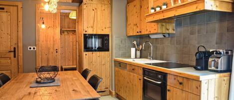 Una cocina moderna con armarios de madera, una mesa de comedor y varios electrodomésticos, incluyendo un microondas, horno y tostadora.