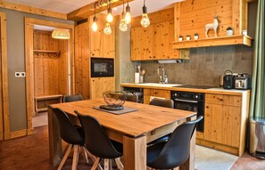 Une cuisine moderne avec des meubles en bois, une table à manger avec des chaises et divers appareils électroménagers.