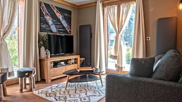 Ein Wohnzimmer mit Flachbildfernseher, einer Holzunterhaltungsecke, einer Couch und einem gemusterten Teppich.