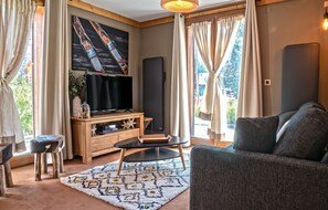 A living room with a flat-screen TV, wooden entertainment unit, a sofa, and a patterned rug. - Homerez - Apt. Mountain View - Les Deux Alpes (Les Deux Alpes)