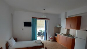 Una habitación con dos camas de madera, un rincón americano y una puerta corrediza de vidrio que da a un espacio al aire libre.