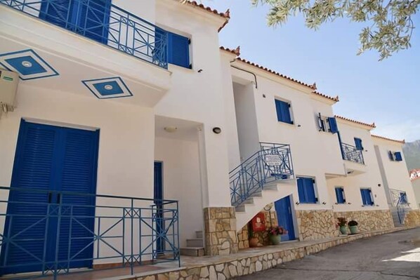 Un edificio blanco con contraventanas azules y fachada de piedra.
