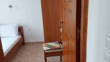 Una habitación con una cama, una silla de madera y una puerta.