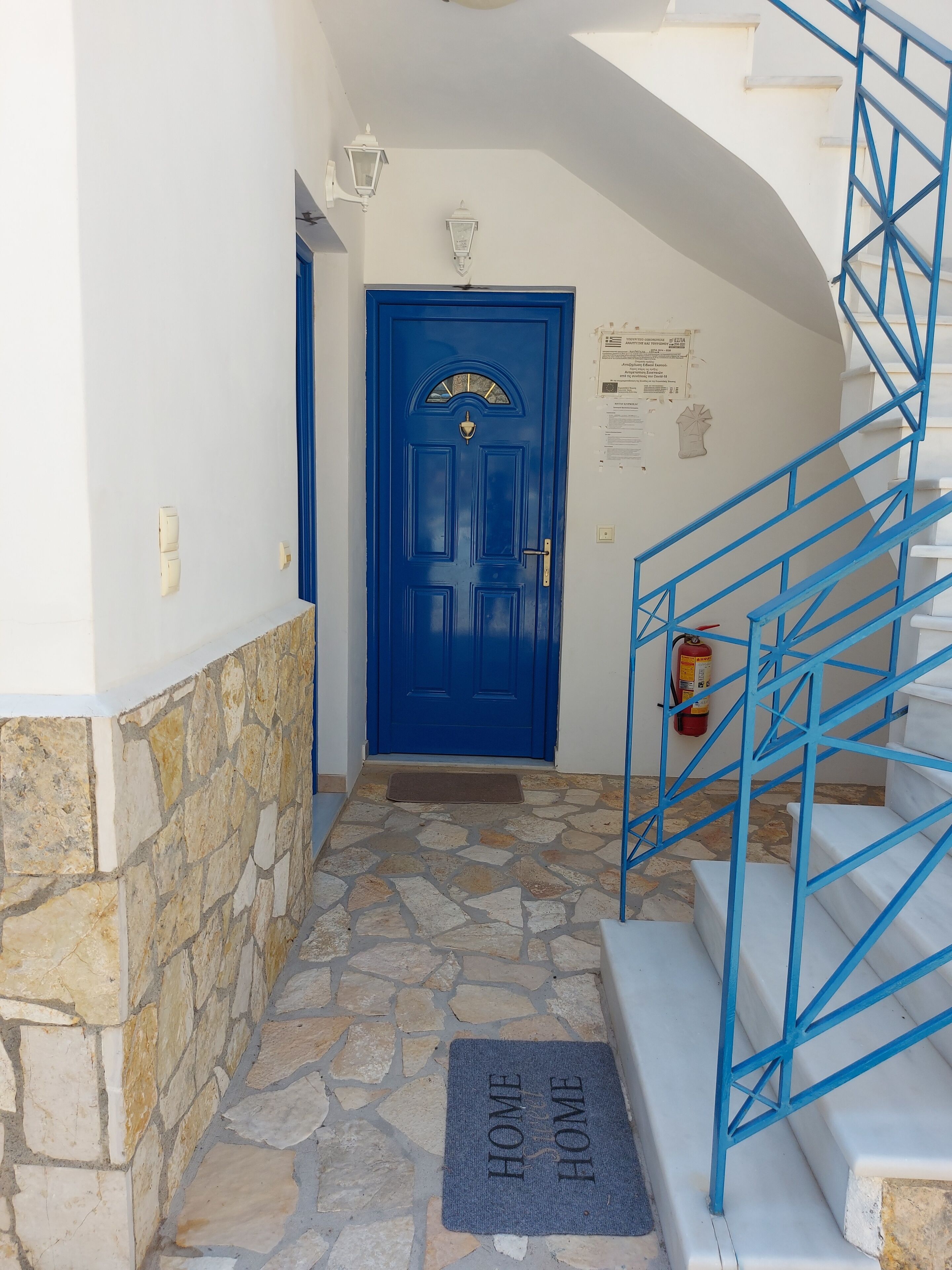 A blue door with a stone wall and a blue staircase leading to a landing.
