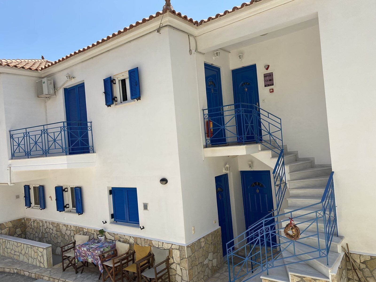 Un bâtiment à deux étages, doté de volets bleus, de fondations en pierre et d’une façade blanche.