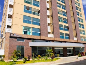 A multi-story hotel with a brick facade, large windows, and a covered entrance area.