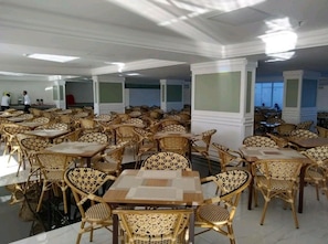 A spacious dining area with multiple tables and chairs, featuring a modern design with patterned upholstery.