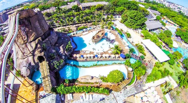 A resort with multiple swimming pools, a large rock formation, and lush greenery.