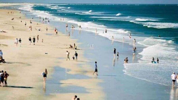 A beach with people walking and swimming. - South Hampton 75” TV Golf Club Saint Augustine Golf Course View! (St. Augustine)