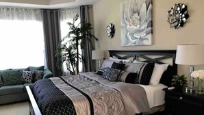 A modern bedroom with a large bed, a bedside table, a lamp, and a decorative wall piece. - South Hampton 75” TV Golf Club Saint Augustine Golf Course View! (St. Augustine)