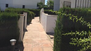 Un chemin menant à un bâtiment moderne doté de nombreux balcons, avec un ciel dégagé.