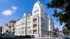 A multi-story building with a prominent corner tower and a red roof. - Comfortable Studio in the Center | Close to the Park and the Fair (Poznan)