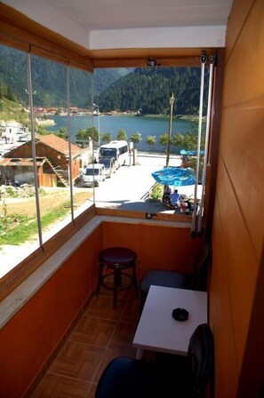 Un petit balcon avec vue sur un lac et des montagnes, une table et une chaise.