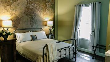 A neatly made bed with a world map on the wall, two bedside lamps, and a window with curtains.